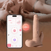 A smiling woman lies in bed. In the foreground, a smartphone displays the control app beside the Colter Thrusting Large 8.5" Realistic App Controlled Dildo with Clit Licker, showcasing remote and app-controlled features for enhanced pleasure.
