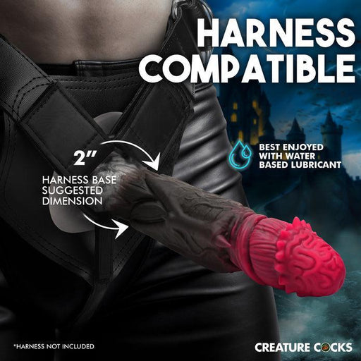 A person wearing a strap-on harness with a realistic, Dracula-themed dildo attached. The Count Cockula Vampire Fantasy Silicone Dildo from XR Brands is detailed with a textured, vein-like design and features a red, fleshy tip. Text overlays indicate it's phthalate-free silicone, harness compatible, and best enjoyed with water-based lubricant.