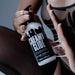 Dressed in sheer black, a person dispenses Creamy Glide Milky Semen-Style Cum Lubricant (8.5 fl oz), a silky water-based gel, from its pump bottle, holding it between their hand and thigh.