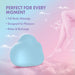 The Cuddle Cloud External Palm Sized Vibrator, a blue cloud-shaped silicone toy, rests on pink clouds beneath a pastel sky. Text: "Perfect for every moment – Full-body massage, Designed for pleasure, Relax & recharge." Floating legs and bubbles nearby.