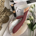 The Metis Touch Panel Rabbit Vibrator in burgundy and rose gold rests on a large shell on an open magazine, surrounded by two lipstick tubes, white flowers, and decorative accents.