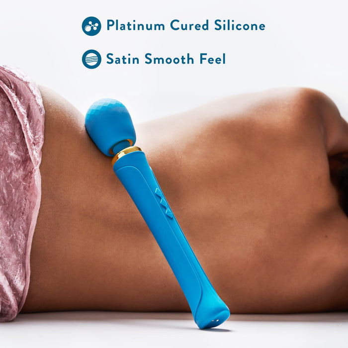A luxurious Dianna Rechargeable Rumbly Waterproof Wand Vibrator from Blush rests against a person’s side, who is lying down on their stomach on a soft surface. Text above the massager reads "Body Safe Platinum Cured Silicone" and "Satin Smooth Feel" with accompanying icons. Enjoy its premium vibrating patterns for ultimate relaxation.
