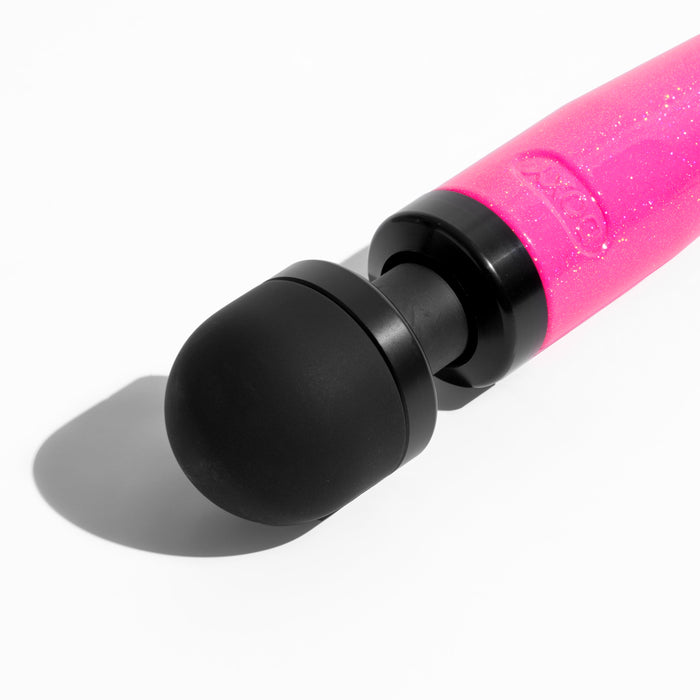 A close-up of the Doxy Die Cast 3 Compact Wand Vibrator Hot Pink against a white background. The compact powerhouse from Doxy features a black round head and a pink glittery handle, casting a soft shadow on the surface.
