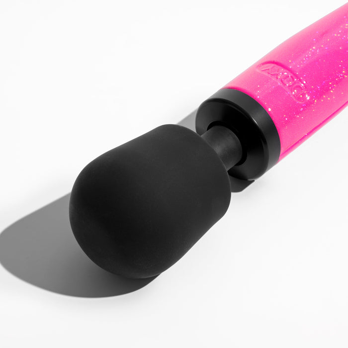 Close-up image of the Doxy Die Cast Extra Powerful Wand Vibrator in hot pink, featuring a black, rounded, cushioned head. The pink handle boasts a subtle glittery finish and casts a shadow on a white surface. This wand massager provides deep rumbly vibrations comparable to the renowned Doxy brand for ultimate relaxation.