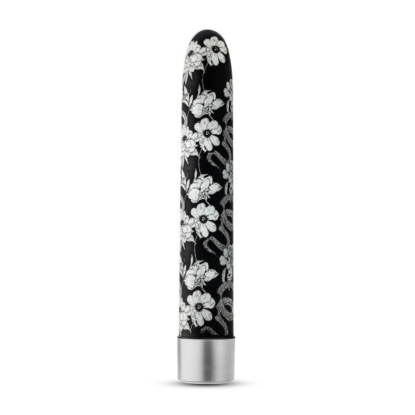 The Eden Black Floral Slim Beginner Bullet Vibrator by Blush features a sleek, black cylindrical design adorned with intricate white floral patterns. Its metallic silver base contrasts beautifully with the elegant floral surface, allowing the classic slimline vibrator to stand upright against a plain white background and offering powerful vibration modes.