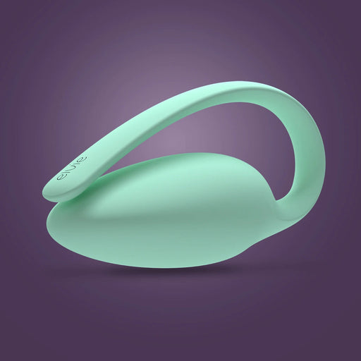 The Elvie Trainer Smart Kegel Exerciser, a mint green, oval-shaped device with a curved handle and "elvie" branding, is shown on a purple gradient background. Its design is sleek and modern.