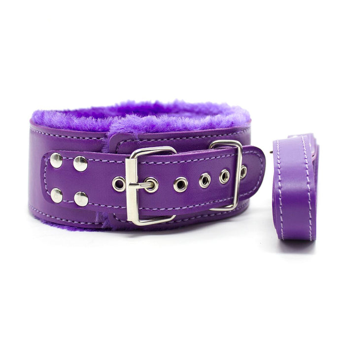 Experience the Ple'sur Everything Bondage 9 Piece Beginner's Bondage Kit - Purple, featuring a purple leather collar with a metal buckle and eyelets. This exquisite piece boasts a soft, fluffy purple lining for unparalleled comfort. The sensory thrill is heightened when displayed against a white background with a matching purple strap placed beside it, making it an ideal option for beginners exploring the world of bondage.