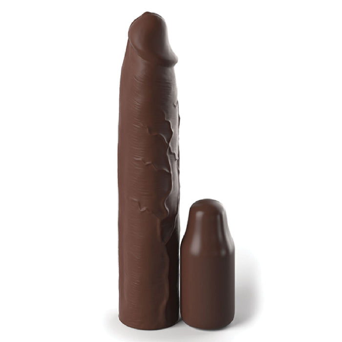 A Fantasy 9 Inch Silicone Penis Extension with a 3 inch Plug from Pipedream Products, in a rich chocolate color, stands vertically next to a shorter, similarly colored cylindrical object. Their texture and shape resemble that of chocolate figures. The taller object features an irregular surface design typical of a silicone sleeve.