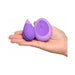 A hand holding a pair of purple Fantasy For Her Remote Controlled Kegel Exercisers by Pipedream Products, with one slightly larger than the other. Both devices have smooth, rounded surfaces and provide discreet vibration. They are compact enough to fit comfortably in the palm, making them ideal for pelvic floor workouts.