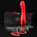 A luxurious red ergonomic adult toy with a curved design is displayed as the Fantasy For Her Ultimate Pleasure Double Ended Vibrator 24 K Gold Luxury Edition by Pipedream Products. It comes with three detachable silicone attachments, a sleek black carrying case, and an elegant black gift box adorned with a red bow. The toy features convenient control buttons on its handle for precise g-spot stimulation, set against a dark background.