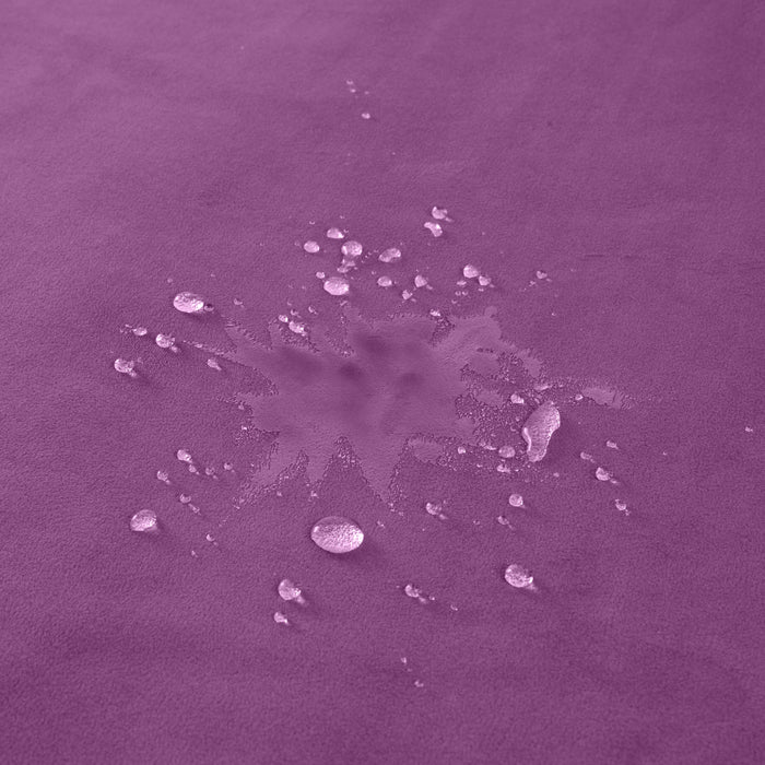 Water droplets and a splash are visible on the smooth, purple surface of the Liberator Fascinator Throw King Size Waterproof Sex Blanket, highlighting its effective moisture barrier after a recent spill or liquid contact.