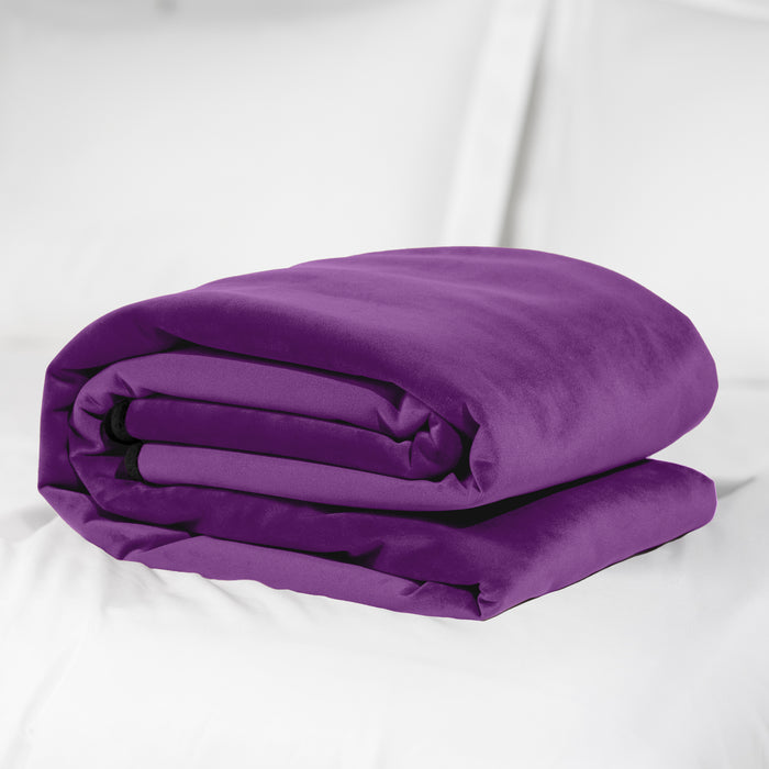 A Liberator Fascinator Throw Queen Size Waterproof Sex Blanket in purple is neatly folded on a white bed with white pillows in the background.