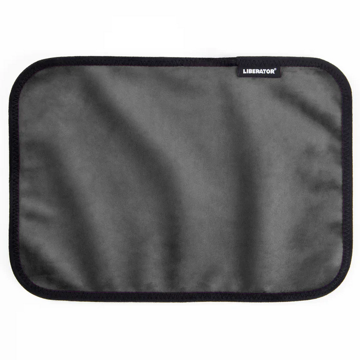 The Liberator Fascinator Toy Pad is a rectangular gray moisture-proof mini mat with rounded corners, black trim, and a small "Liberator" label in the upper right corner. The soft, smooth microfiber surface is likely machine-washable.