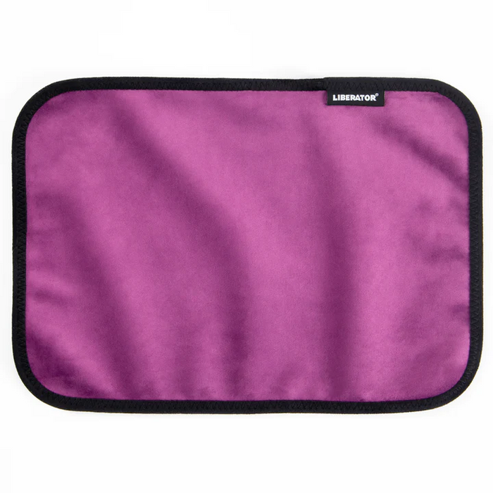 The Liberator Fascinator Toy Pad is a rectangular purple mini mat with black trim and a small "LIBERATOR" label in the top right corner, shown flat on a white background. This moisture-proof pad is machine-washable for easy cleaning.