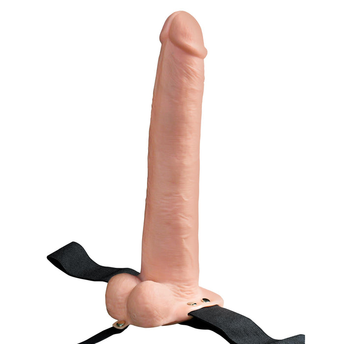 The 11-inch Fetish Fantasy Vibrating Hollow Dildo with Balls & Strap-on Harness in Vanilla has an adjustable strap-on design featuring black straps with metal rivets. The plain white background accentuates its cylindrical, flesh-like form.