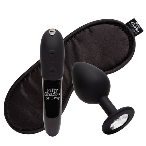 The Fifty Shades of Grey Come to Bed Kit, in black, features a blindfold, jeweled-base butt plug, and matching vibrating wand for couples’ sensual play, displayed on a white background.