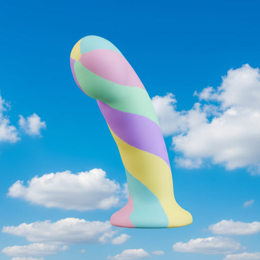 The Daydream Smooth Slim Silicone Dildo with Suction Cup, in pastel swirls and made from body-safe silicone, is centered against a bright blue sky with scattered white clouds.