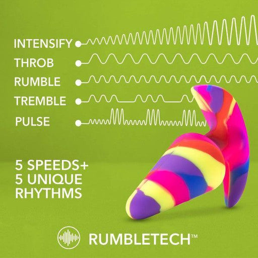 A vibrant, multicolored, abstract-shaped object set against a green backdrop features text that highlights its capabilities: "INTENSIFY, THROB, RUMBLE, TREMBLE, PULSE - 5 Speeds + 5 Unique Vibration Patterns." This butt plug is crafted from premium platinum-cured silicone and is perfect for beginners. At the bottom, the RumbleTech logo is prominently displayed. The product is called "Free Spirit Vibrating 10 Function Beginner Silicone Butt Plug" by Blush.