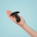 A hand holds the Fun Factory Bootie Medium Silicone Anal & Prostate Plug, a small, black, plug-shaped object made of smooth silicone, against a light blue background. The plug features a curved design with a flared base for a comfortable grip and is ergonomically shaped for prostate fun. The hand's open palm prominently displays the product.