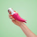 A hand with red nail polish holds the sleek Fun Factory Volta Rechargeable External Vibrator in Petrol Blue against a light green background.