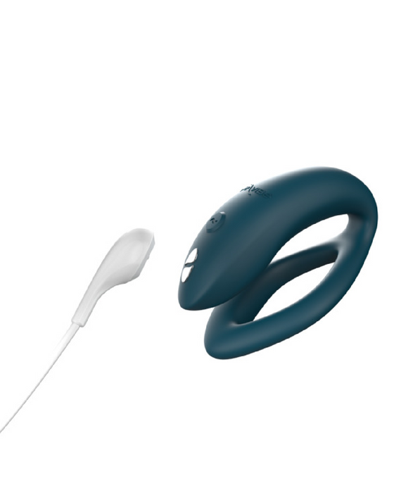 A sleek We-Vibe Sync O Hands-Free Wearable Couples Vibrator - Green with a modern design next to waterproof white earbuds against a neutral background.
