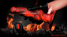 A gloved hand holds a Hell Wolf Thrusting & Vibrating Silicone Werewolf Dildo with Remote above a fiery background, near a black canister labeled with control buttons. The scene suggests a dramatic, fantasy-themed setting featuring XR Brands.