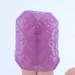 A hand holding a Tenga Uni Amethyst Textured Finger Sleeve for Stroking and Clit Massage, slowly rotating to display all sides against a light background.