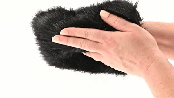 A person engaging in sensory play by stroking a Spiked and Furry Black Sensory Mitt from Sportsheets with their hand.