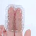 A hand holds a translucent, intricately carved crystal stone with pink tones, rotating it to display its detailed geometric patterns and sparkling facets against a plain white background.