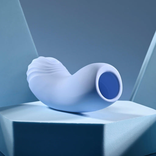 A sleek, modern light blue Good Point G Spot Finger Vibrator with a flexible, curved design rests on a matching geometric pedestal. The background's blue shades enhance its form and evoke fluidity akin to g-spot pleasure.