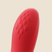 Close-up of the tip of the Fortexa Kinky Finger Rabbit Vibrator with App Control, featuring red silicone and a diamond-textured pattern, shown on a smooth surface against a light beige background.