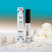 A tube and box of Hot Kiss Arousal Lip Gloss - Coconut 7ml are surrounded by white coconut candies and coconut flakes, set against a gradient blue and beige background.