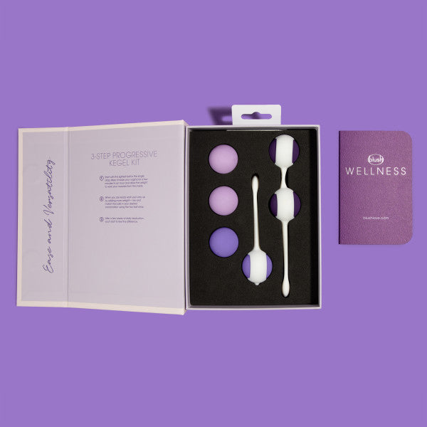 An open box displays the Wellness Kegel Ball Training Kit for Pelvic Floor Health with three pairs of purple and white kegel balls, an instruction booklet on the left, and a purple wellness guide on the right, all against a purple background.