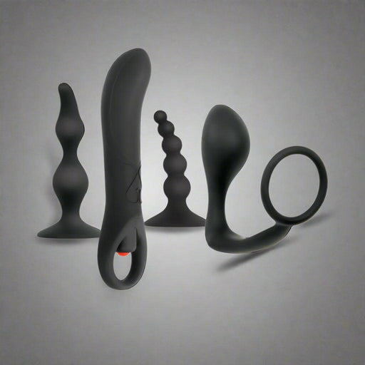 A collection of Evolved Novelties' Intro To Prostate Kit 4 Piece Silicone - Black, featuring variously shaped and textured adult toys like plugs and rings, along with a vibrating prostate massager, displayed against a white background.
