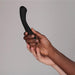 Two hands holding a Je Joue Juno Flex G Spot Vibrator - Black against a plain background. The darker hand grasps the Je Joue product, while the lighter hand gently supports the wrist, creating a sense of connection and unity.
