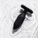 The Je Joue Onyx Large Powerful Remote Control Vibrating Butt Plug, in black silicone with a T-shaped base, rests on rippled white water, its circular patterns hinting at deep rumbly vibrations ready to be explored.