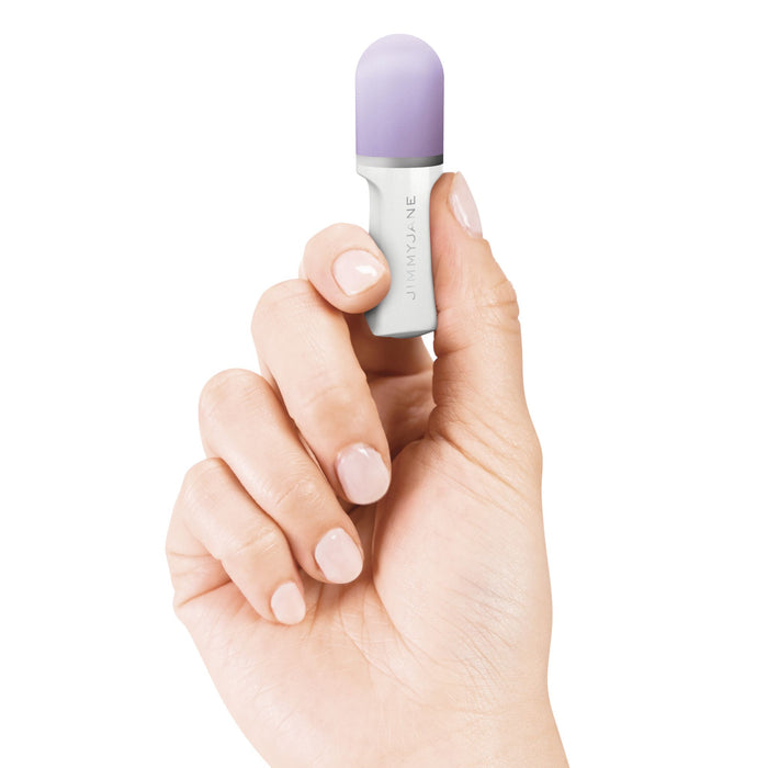 A hand with neatly manicured nails holds a small, cylindrical object featuring silicone finger grips, a light purple cap, and a white body. The brand name "Pipedream Products" is printed on the side of the object. The background is white.