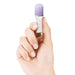 A hand with neatly manicured nails holds a small, cylindrical object featuring silicone finger grips, a light purple cap, and a white body. The brand name "Pipedream Products" is printed on the side of the object. The background is white.