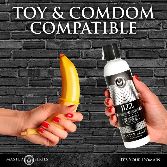 A hand holds a banana with a condom, while another displays a bottle of Jizz Ultra Realistic Unscented Cum Lube. "Toy & Condom Compatible" text appears above against a brick wall background.