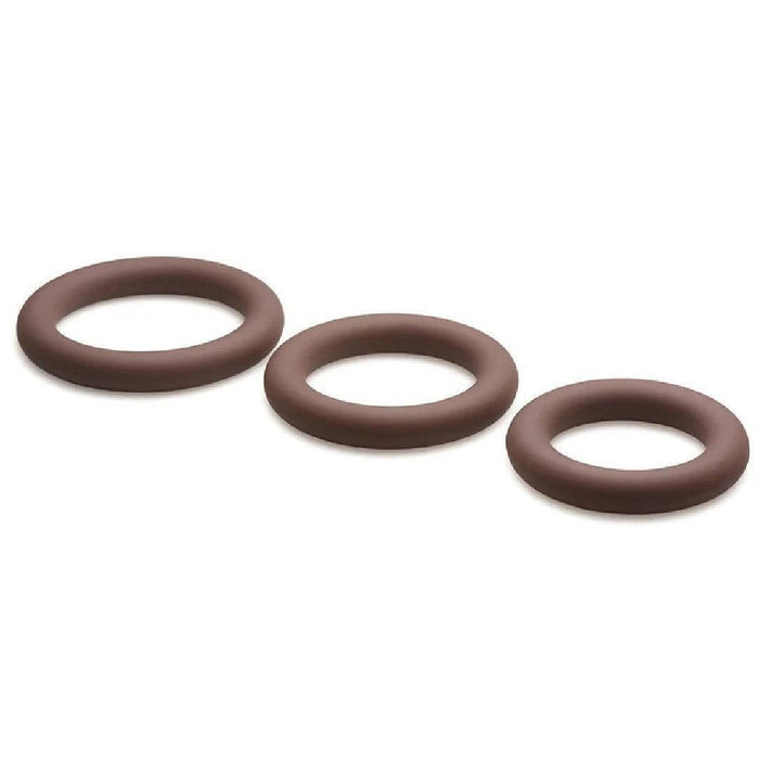 Three "Jock Discreet Stretchy Silicone Cock Rings," varying in graduated sizes from small to large, are arranged in a diagonal line from left to right. The stretchy silicone rings have smooth surfaces and are situated on a plain white background. This set of three cock rings, available in Chocolate, is produced by Curve Toys.