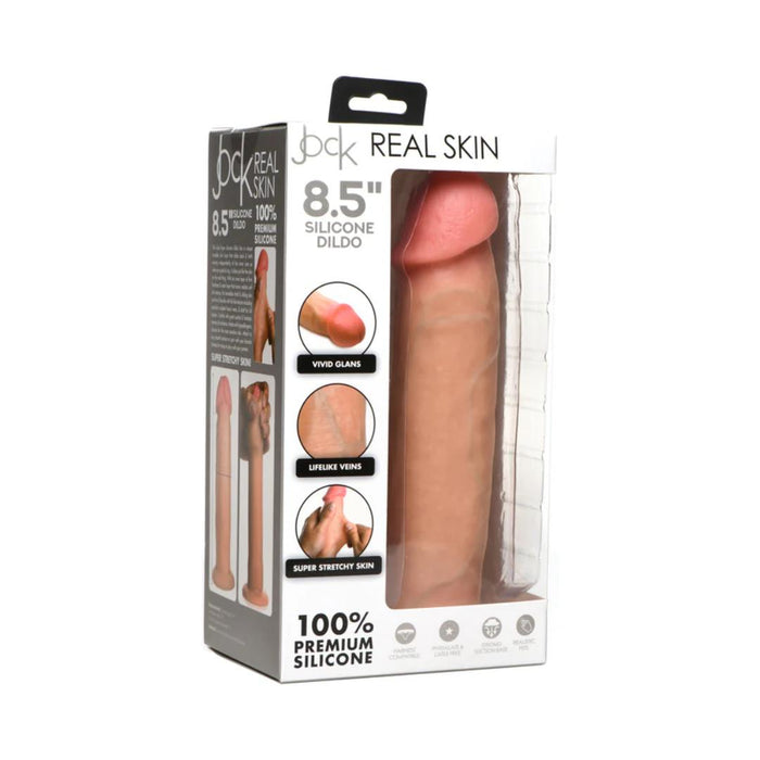 The image displays a box containing the "Jock Real Skin 8.5 Inch Silicone Suction Cup Dildo - Vanilla" from XR Brands. The product is highlighted with features like "Vivid Glans," "Lifelike Veins," and "Super Stretchy Skin." The packaging is designed to emphasize these realistic and stretchable characteristics, complete with detailed images and descriptions.