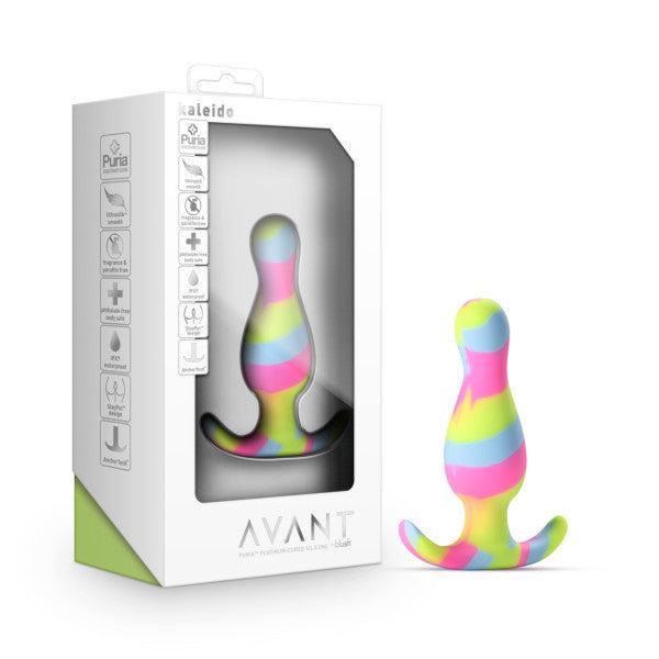 The Kaleido Silicone Beginner's Butt Plug, featuring a vibrant striped design and made from premium platinum-cured silicone, boasts a curved base and is displayed next to its white packaging box. The box has a clear front window showcasing the toy inside and includes various product icons along with the brand name "Blush" prominently featured.