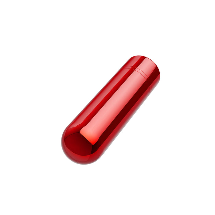 A red, glossy, cylindrical object resembling a capsule, placed upright against a plain white background. The Kool Vibes Rechargeable Mini Bullet by Blush has a smooth surface with a reflective sheen, indicating a shiny finish. Its classic shape and travel-friendly design make it an essential companion for any journey.