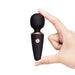 A hand holds the Le Wand Micro Powerful Pocket Sized Wand upright against a white background, highlighting its sleek black and rose gold design—ideal for deep, rumbly vibrations in a compact, travel-friendly vibrator.