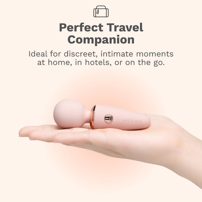 A hand holds a small, pink wand-shaped personal massager. Text above reads: "Perfect Travel Companion. Ideal for discreet, intimate moments at home, in hotels, or on the go.