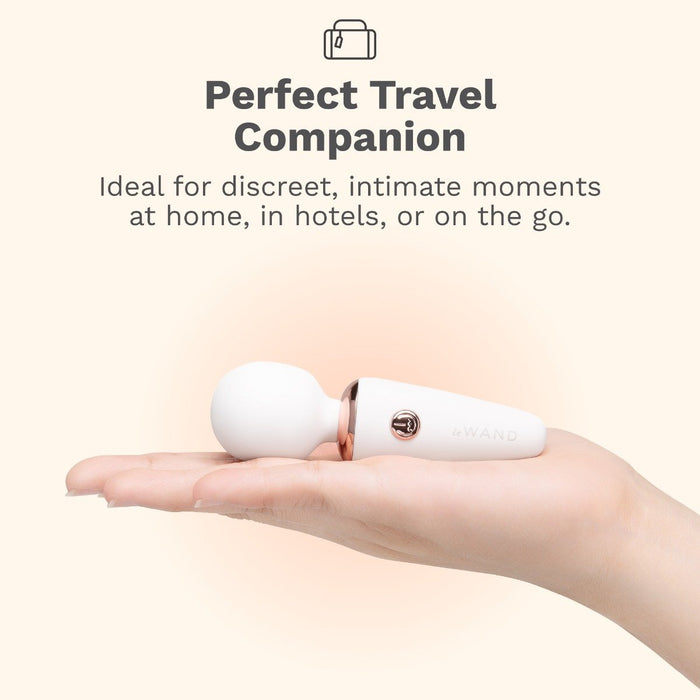 A hand holds the Le Wand Micro Powerful Pocket Sized Wand, a small white mini massager with a round head. Text above reads: “Perfect Travel Companion—deep rumbly vibrations for discreet pleasure at home, in hotels, or on the go.”.