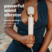 A person in a navy blue outfit holds a Le Wand Plug In Powerful Wand Vibrator - Cream against their chest. Text reads: "Powerful wand vibrator with 10 vibration levels. Award-winning toy for solo play or couple's fun.