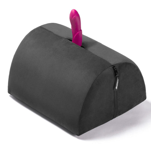 The Liberator BonBon Rideable Sex Toy Mount is a black, semi-cylindrical cushion with a zippered side and a pink silicone sex toy mounted vertically at its center.