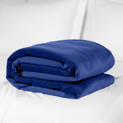 A neatly folded Liberator Fascinator Throw Queen Size Waterproof Sex Blanket in dark blue rests on a white surface, with white bedding in the background.