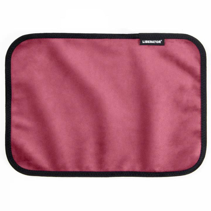 The Liberator Fascinator Toy Pad – Moisture-Proof Mini Mat is a rectangular, rose-colored microfiber pad with black trim and a small "LIBERATOR" tag. This machine-washable mat is shown on a white background.
